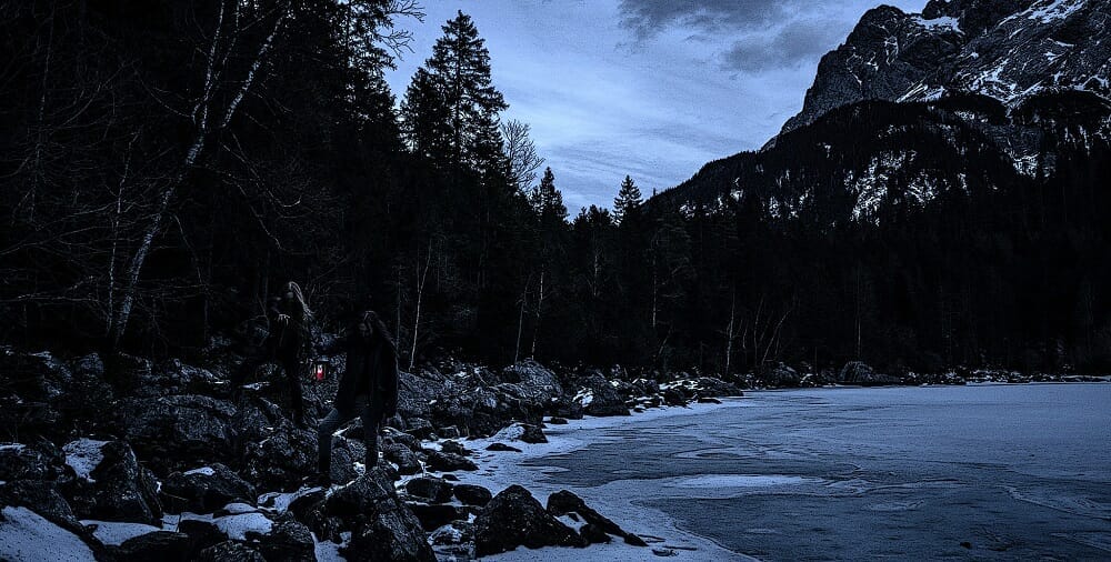 Bandfoto der Band Gràb, die Musiker stehen im Dämmerlicht an einem See
